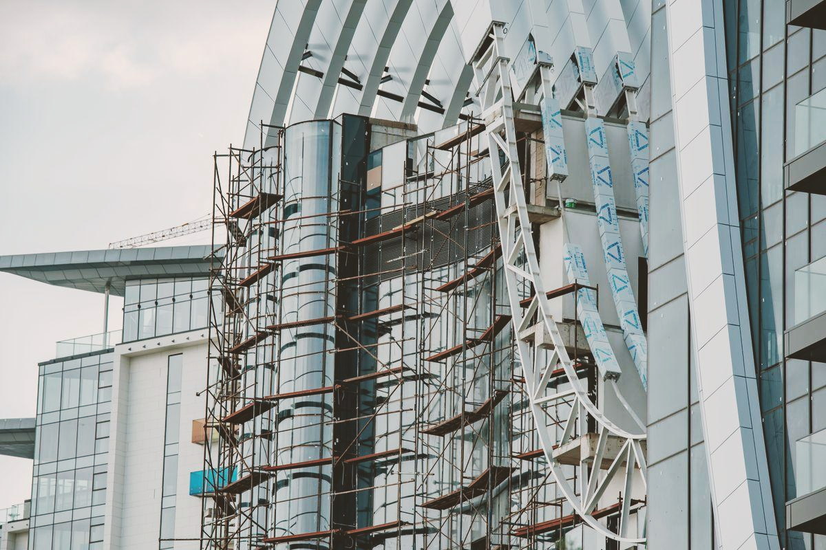 A modern building under construction, steel frame and scaffolding rising into the sky