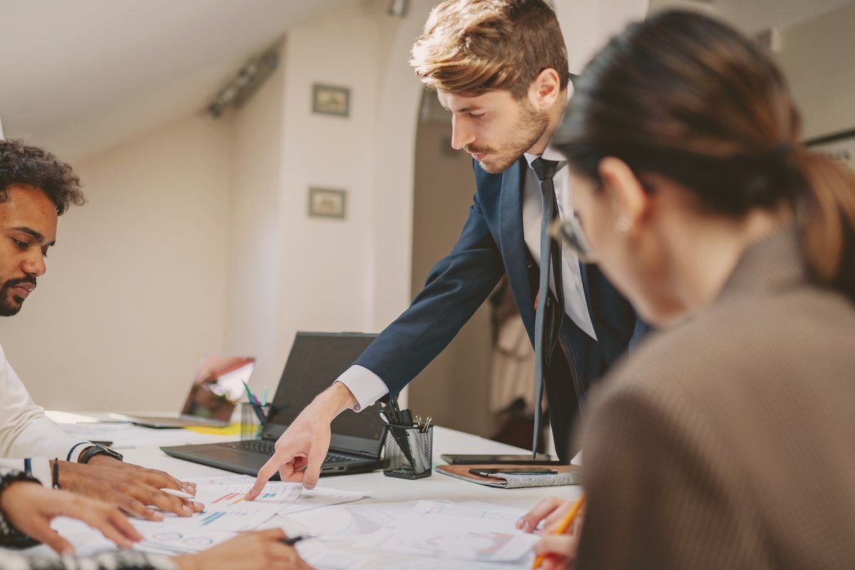 A diverse team gathered around a conference table as their manager brings the discussion together