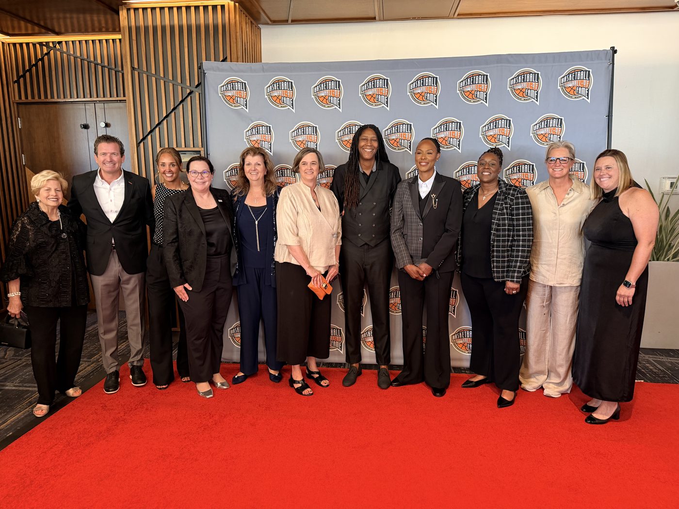 Michelle Snow with the Naismith Basketball Hall of Fame class in front of a red step-and-repeat backdrop